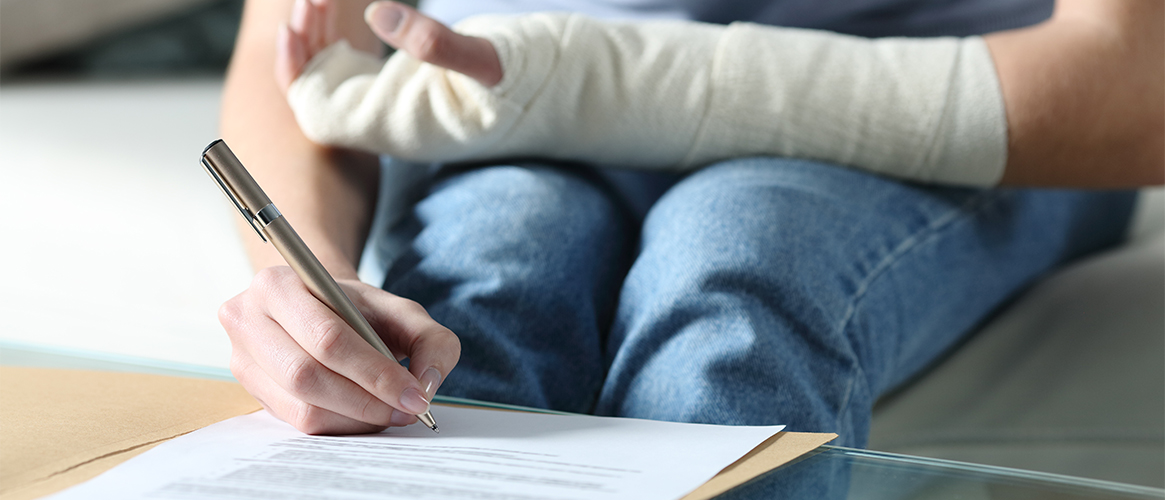 Woman with an arm cast fills out a form on a table.