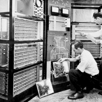 Employees work on the hardware of a room-sized mainframe computer in 1955. Employees work on the hardware of a room-sized mainframe computer in 1955.